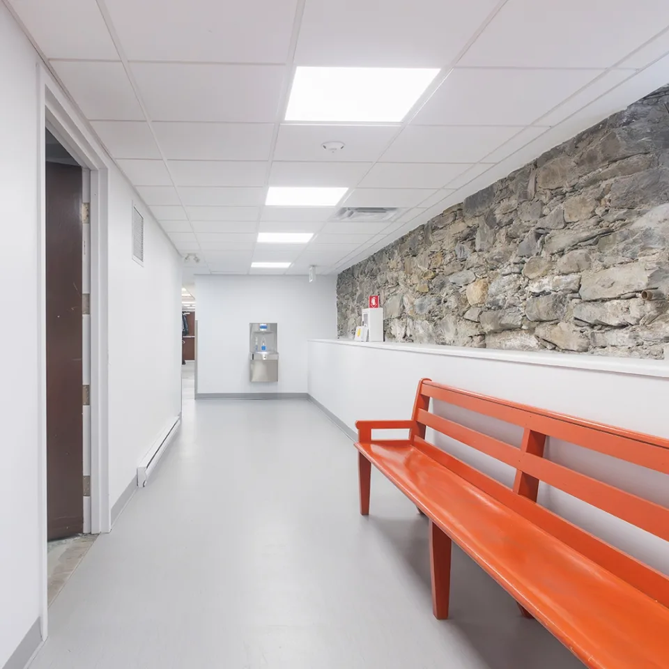 Banc orange dans le couloir d'un sous-sol avec un demi-mur de pierre